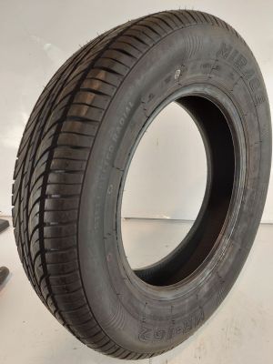 un gros plan d'un pneu posé sur une surface blanche, avec un roitelet à côté
