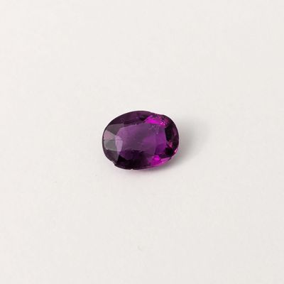 gros plan d'une pierre précieuse violette sur une surface blanche