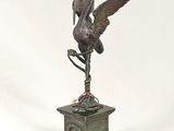 bronze statue of a bird on a pedestal with a bird on it ' s head