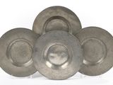 trois assiettes en argent sont empilées les unes sur les autres sur une surface blanche