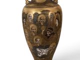 a gold vase with skulls on it on a white background
