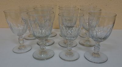 six empty wine glasses are lined up on a white table