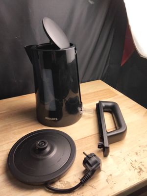 une cafetière noire posée sur une table en bois, avec une télécommande
