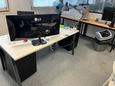 a desk with a computer monitor and a printer on it