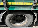 a green truck with a yellow stripe parked on the side of the road