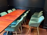 une longue table en bois avec des chaises vertes au milieu de la pièce