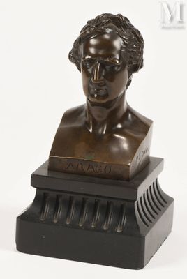 un buste antique en bronze représentant un homme aux cheveux bouclés, posé sur un socle