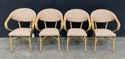 quatre chaises aux sièges rembourrés de couleur beige, placées devant un mur noir