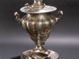 silver plated urn with lid on stand on grey background