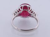 a close up of a ring with a ruby stone surrounded by diamonds