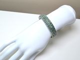 bracelet with green stones on a white mannequin hand