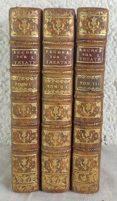 three old books are lined up on a table
