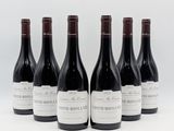 six bottles of wine are lined up in a row on a white surface