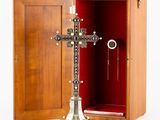 une image représentant une croix en argent dans un coffret en bois, à côté d'une bague