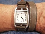 a person wearing a watch on their wrist with a leather band