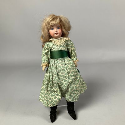 poupée aux cheveux blonds, vêtue d'une robe verte et de bottes noires