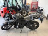 a black motorcycle parked in a showroom with other motorcycles