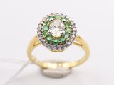 a close up of a diamond and emerald ring on a white surface