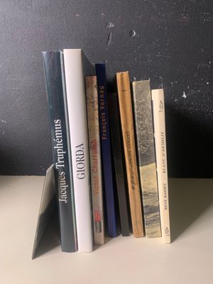 Plusieurs livres sont alignés sur une étagère devant un mur noir