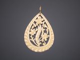 a gold tear shaped pendant with a floral design