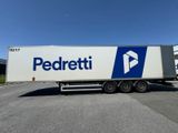 un semi-remorque blanc, arborant un logo bleu et blanc, garé devant un immeuble