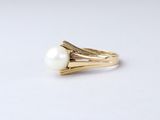 a close up of a gold ring with a white pearl