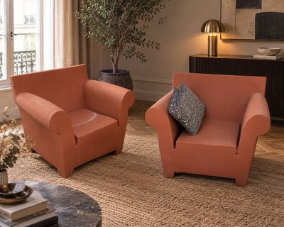 two orange chairs in a living room with a plant in the corner