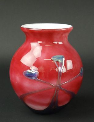 un vase rouge posé sur une table, sur fond noir