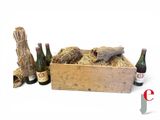 une caisse en bois remplie de bouteilles de vin, à côté d'un tas de foin