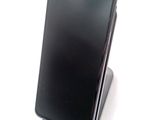 the back of a black cell phone sitting on top of a stand