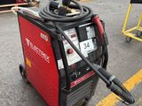 a red and black welding machine in a parking lot