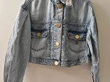 une veste en jean suspendue à un cintre accroché au mur