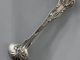 an antique silver spoon with a spoon handle on a gray surface
