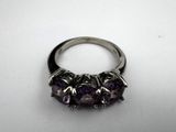 a close up of a ring with purple stones on a white surface