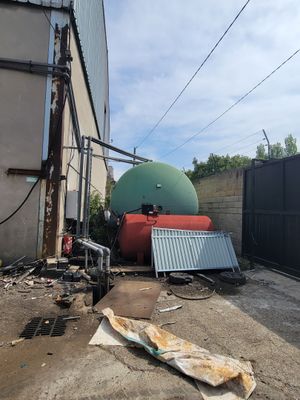 a large tank sitting on the ground next to a fence