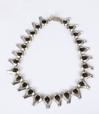 a silver necklace with black stones on a white background
