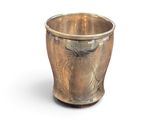 une tasse en argent posée sur une surface blanche