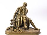 an antique bronze statue of a man sitting on a rock with a dog
