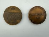 two commemorative coins with names on them sitting on a white surface