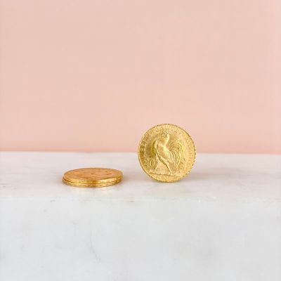a gold coin sitting on top of a marble counter next to a pink wall