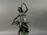 a bronze statue of a woman holding a lamp with a bird in her hand