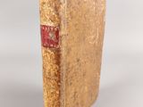 an old book sitting on top of a table next to a white wall