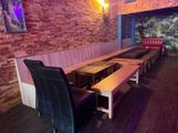 tables and benches in a restaurant with a brick wall behind them