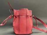 red leather handbag with strap on grey background