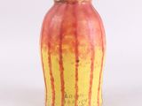 un vase jaune et rouge posé sur une surface blanche