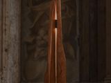 une sculpture en bois d'où émane une lumière dans une pièce sombre