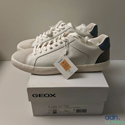 une paire de chaussures blanches et bleues posée sur une boîte blanche