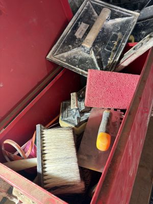 a red box filled with assorted tools and a brush