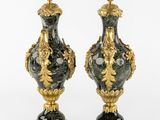 two black and gold vases sitting on top of a white surface