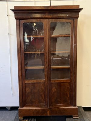 une bibliothèque ancienne en bois avec des portes vitrées dans une pièce
